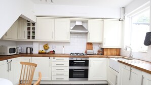 A modern kitchen with white cabinets, a wooden countertop, a gas stove, a microwave, and a sink. - ☀ Sunny, Victorian 2BR Townhouse ☀ Oxford - Pass the Keys (Oxford)