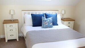 A bedroom with a bed, two bedside tables, a nightstand, a window, and a ceiling light.