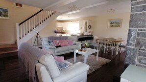 A living room with a white sofa, a grey sofa, a coffee table, and a dining area with a table and chairs.