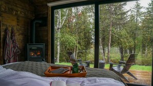 A cozy room with a bed, a book, a tray with a mug, and a fireplace. - Private Vacation Rental Cabin with views on Minnesota's North Shore (Tofte)