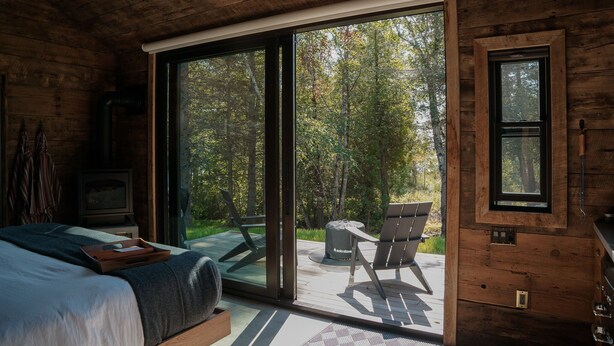 A wooden cabin bedroom with a large sliding glass door leading to an outdoor deck. - Private Vacation Rental Cabin with views on Minnesota's North Shore (Tofte)