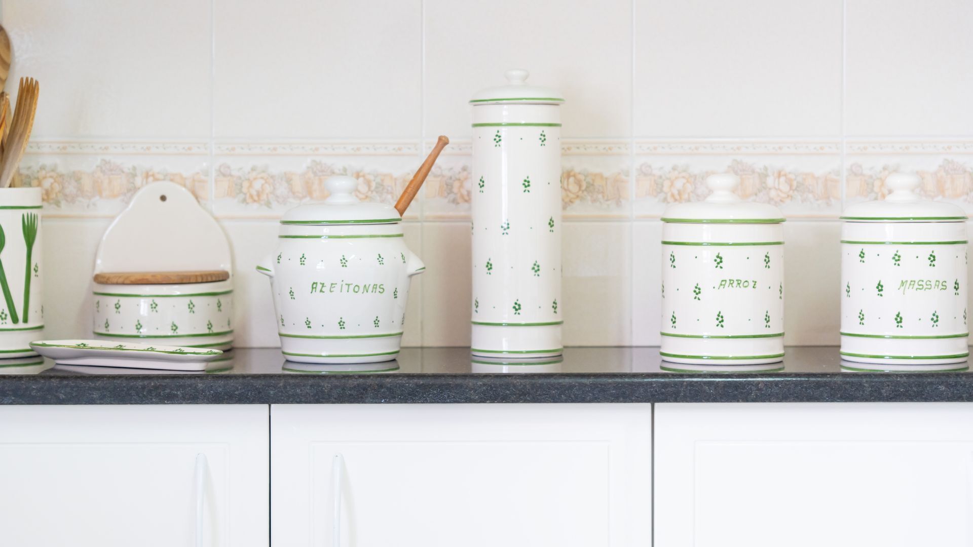 A kitchen counter with white cabinets and a decorative backsplash.