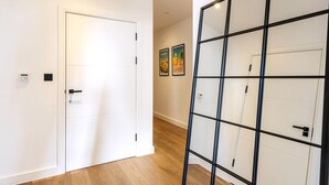 A hallway with a white door, a black-framed glass partition, and two framed pictures on the wall. - City View Spacious 2 Bedroom Penthouse (London)
