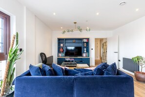 A living room with a blue sofa, a television, and a bookshelf.