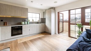 A modern kitchen with grey cabinets, a built-in oven, and a window overlooking a cityscape. - City View Spacious 2 Bedroom Penthouse (London)