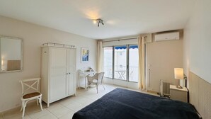A bedroom with a bed, a desk, a chair, a wardrobe, and a window with a view of the outside.