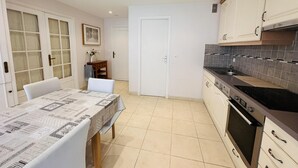 A compact kitchen with a dining table, a stove, and cabinets.