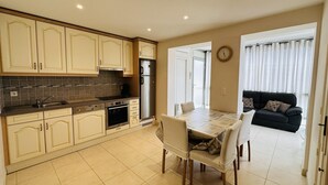 A kitchen with white cabinets, a stainless steel refrigerator, and a dining table with chairs.