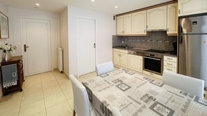 A compact kitchen with white cabinets, a stainless steel refrigerator, and a tiled backsplash.