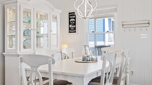 Ein Esszimmer mit einem weißen Tisch, weißen Stühlen und einer Glasvitrine mit Dekorationen.