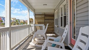 Eine überdachte Veranda mit weißen Stühlen und einer Holzterrasse.