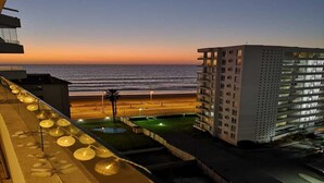 Et hotel med havudsigt i solnedgang, med en moderne bygning, altaner og et poolområde.