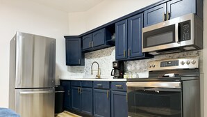 Eine moderne Küche mit Edelstahlgeräten, dunkelblauen Schränken und Holzboden.