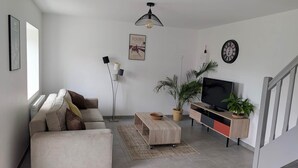 Una sala de estar moderna con sofá, mesa de centro, mueble para televisión y una escalera.
