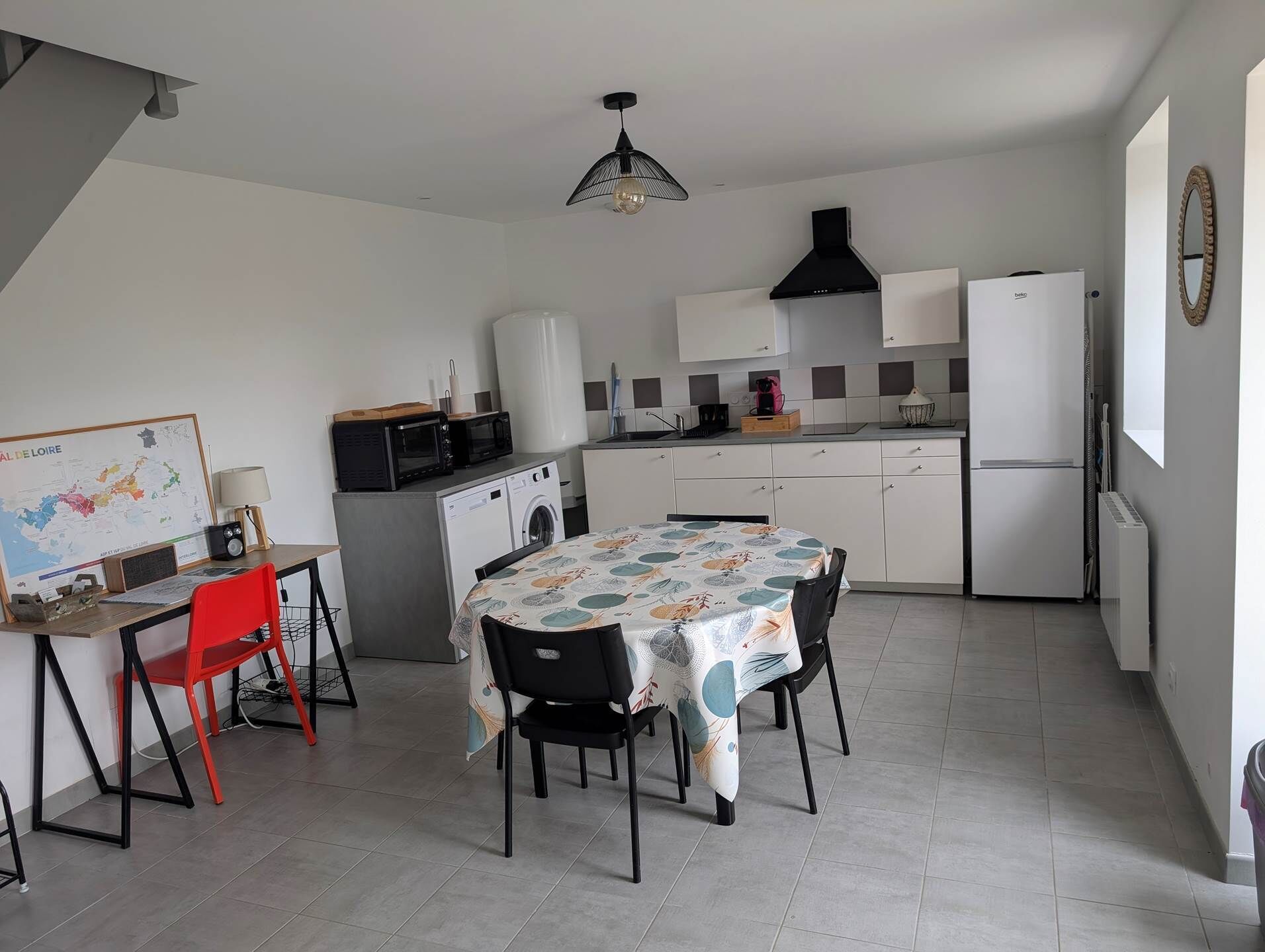 Een compacte keuken met een eethoek, een wasmachine, een magnetron en een koelkast.