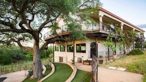 Uma casa de dois andares com varanda, entrada em curva e gramado bem cuidado.