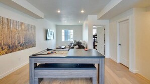 Una habitación amplia con una mesa larga, un cuadro abstracto grande en la pared y un ventanal que proporciona luz natural.