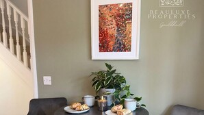 A dining area with two chairs, a table, a potted plant, and a framed artwork on the wall.