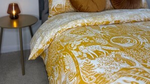 A bedroom with a bed, two pillows, a nightstand, and a lamp.