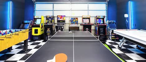 Una sala de jocs amb una taula de futbolí, una taula de ping-pong i diversos jocs arcade.