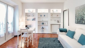 Un salon moderne avec un canapé blanc, une table à manger et des chaises, ainsi qu’une bibliothèque.