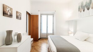 Une chambre à coucher comprenant un lit, une table de chevet et une porte donnant sur un balcon.