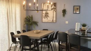 A dining area with a table and chairs, a chandelier, a framed picture, and a hanging plant. - Encantada Resort with lake background. (Kissimmee)