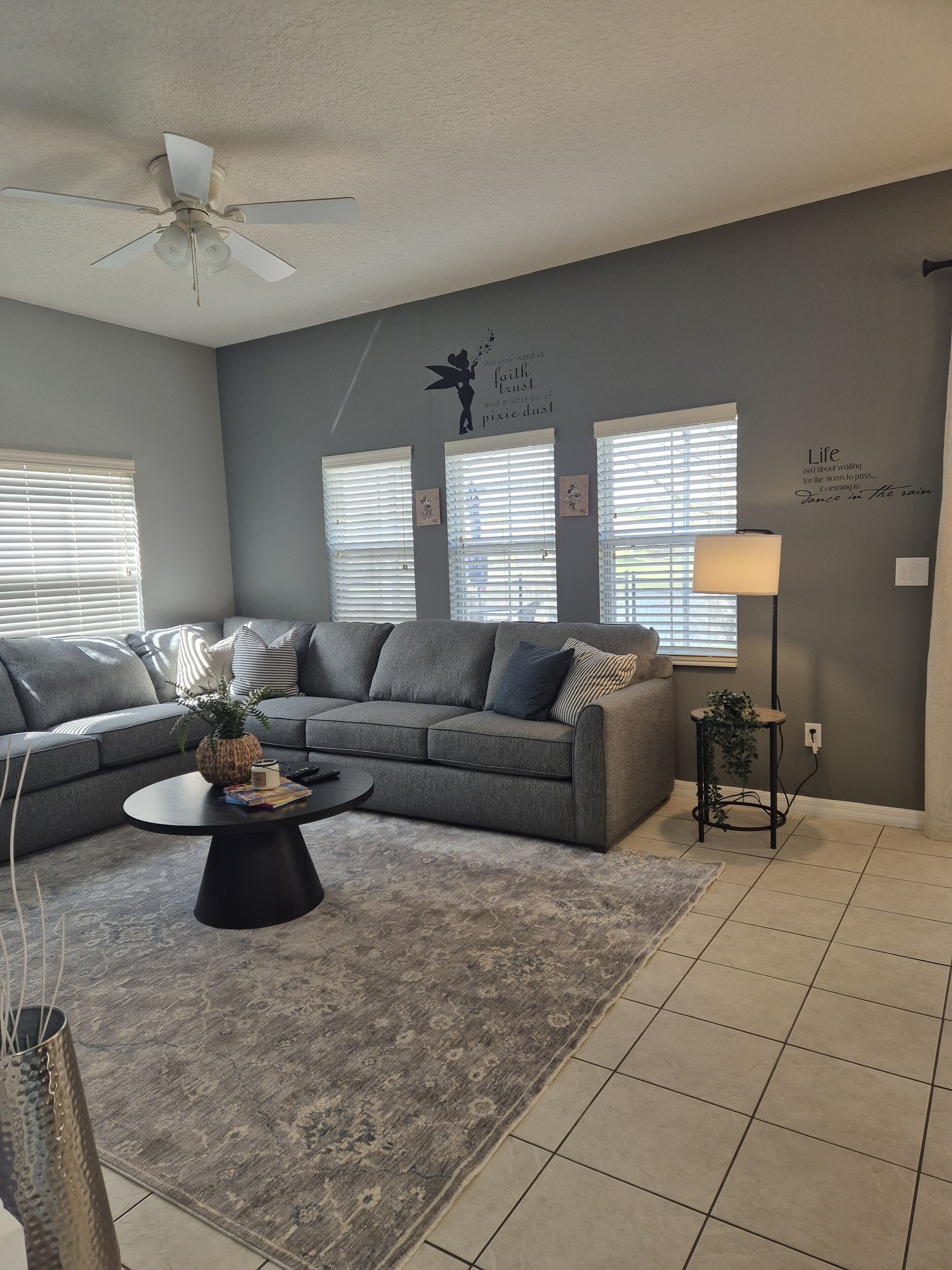 A living room with a gray sofa, a coffee table, a floor lamp, and a ceiling fan.