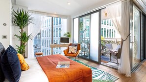 A modern hotel room with a bed, a desk, a chair, a large window, and a balcony. - Idyllic Covent Garden Flat (London)