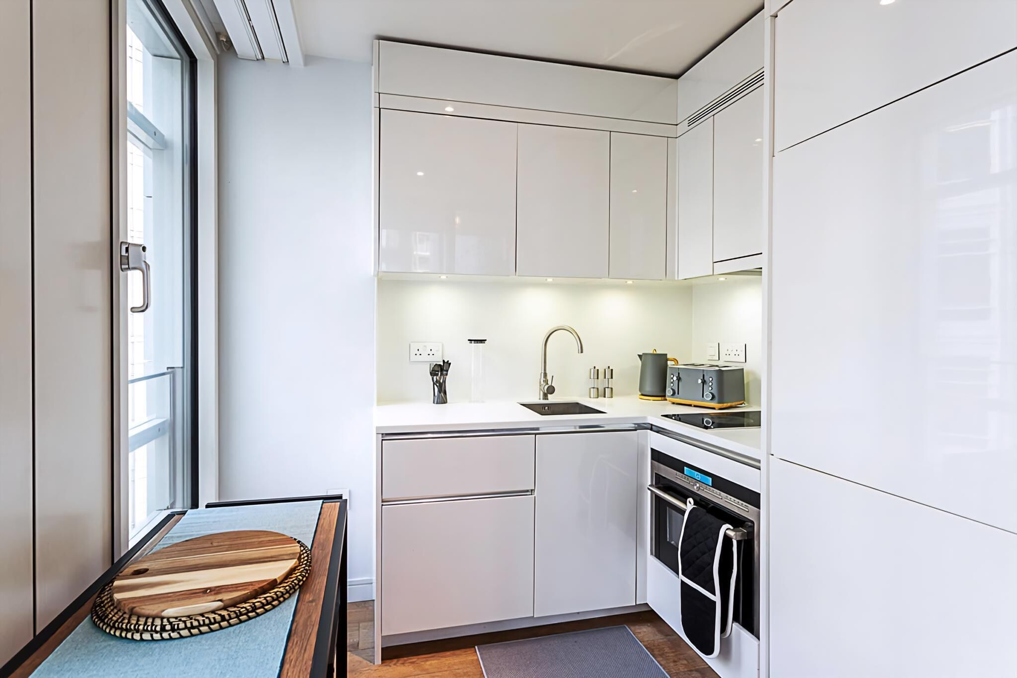A modern kitchen with white cabinetry, a built-in oven, and a sink.