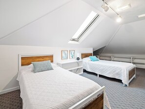 A bedroom with two beds, a skylight, and a white color scheme. - Waterfront sleeps 13 2-Kings/Crib/1st flr sleeper (Port Clinton)