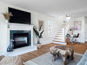 A living room with a fireplace, a staircase, and a seating area. - Waterfront sleeps 13 2-Kings/Crib/1st flr sleeper (Port Clinton)