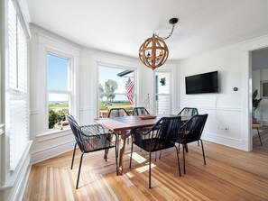 Un coin repas avec une table et des chaises en bois, un lustre et un téléviseur fixé au mur.