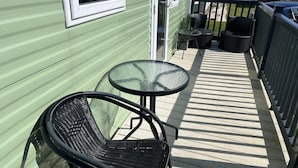 A small outdoor patio with a glass table and two wicker chairs. - Heacham Beach Coastal 2 Bedroom Chalet Retreat (King's Lynn)