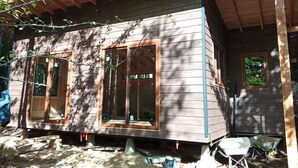 Une cabane en bois dotée de grandes fenêtres et d’un porche abrité.