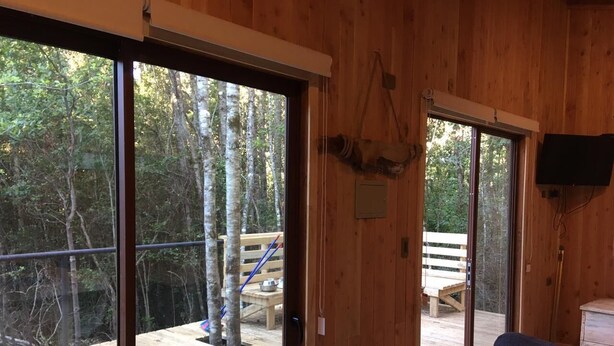 Une cabane en bois dotée de grandes portes-fenêtres coulissantes qui donnent sur une terrasse.