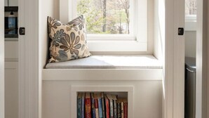 A built-in bench with a window above it, a pillow, and a bookshelf with books. - Blue Ridge Sanctuary: Luxury Retreat at SML (Huddleston)