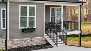 A two-story house with a covered porch, a stone foundation, and a garage. - Blue Ridge Sanctuary: Luxury Retreat at SML (Huddleston)