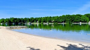 A sandy beach with calm water, trees, and a clear sky. - Blue Ridge Sanctuary: Luxury Retreat at SML (Huddleston)