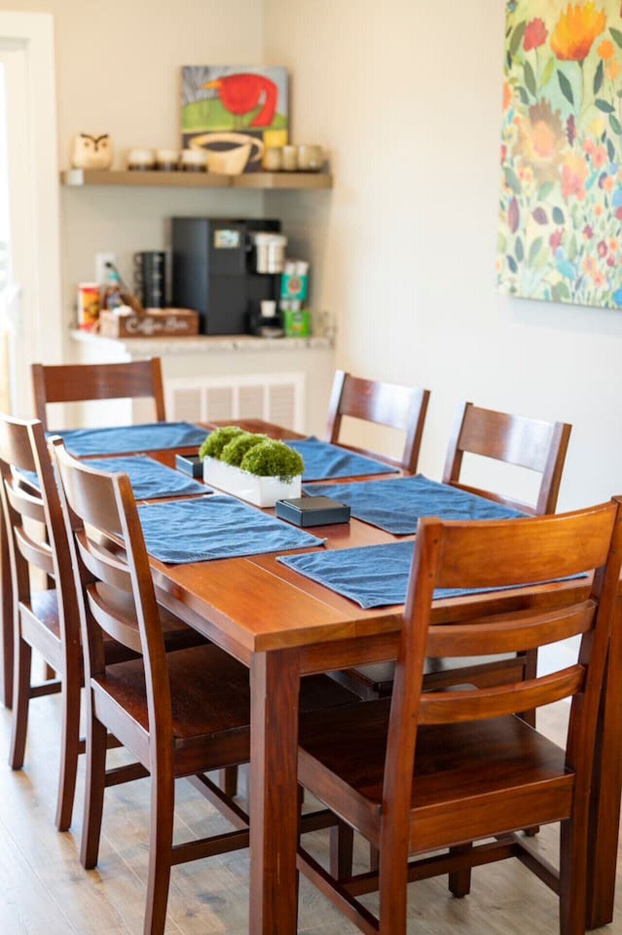 Une table à manger en bois, agrémentée de sets de table bleus, entourée de chaises en bois.