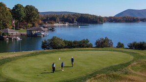 A golf course with a water body and docked boats in the background. - Blue Ridge Sanctuary: Luxury Retreat at SML (Huddleston)