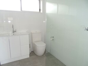 Uma casa de banho moderna com lavatório branco, sanita e zona de duche.