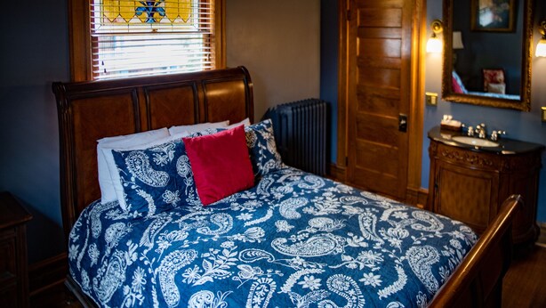 Un dormitorio con cama, radiador, puerta de madera y espejo.