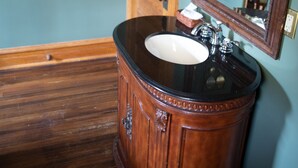 Una cómoda de madera con encimera negra y lavamanos blanco.