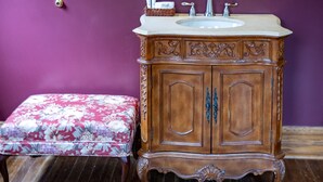 A bathroom with a wooden cabinet, a sink, and a floral bench.