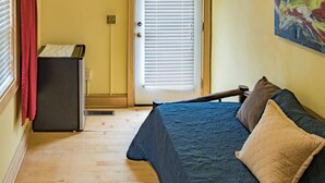 A bedroom with a bed, a radiator, a door with blinds, and a painting on the wall.