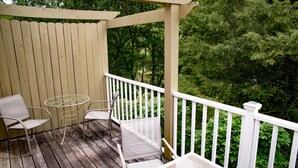 A wooden deck with a white railing, two chairs, and a small table.