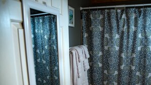 Un baño con cortinas de ducha estampadas y una toalla colgada en un perchero.