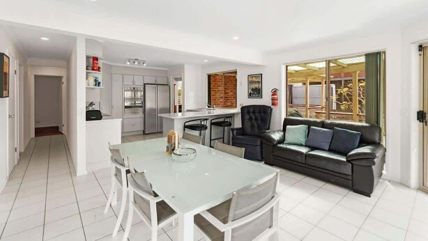 A modern living space with a dining table, a sofa, and a kitchen area.