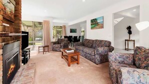 A living room with a fireplace, patterned sofas, a coffee table, and a TV.